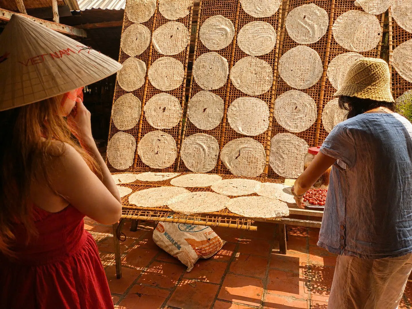 Visitors watching traditional rice paper drying in the sun at a Vinh Long village
