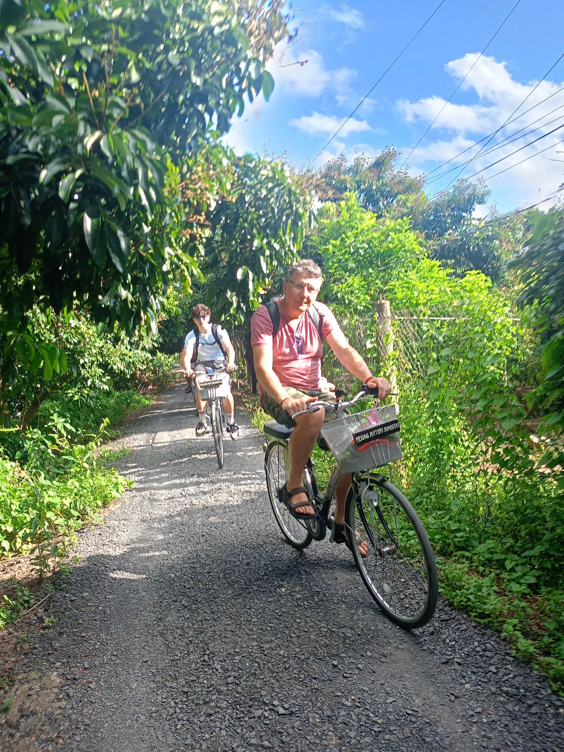 Cyclist riding through a lush green countryside path in Vinh Long