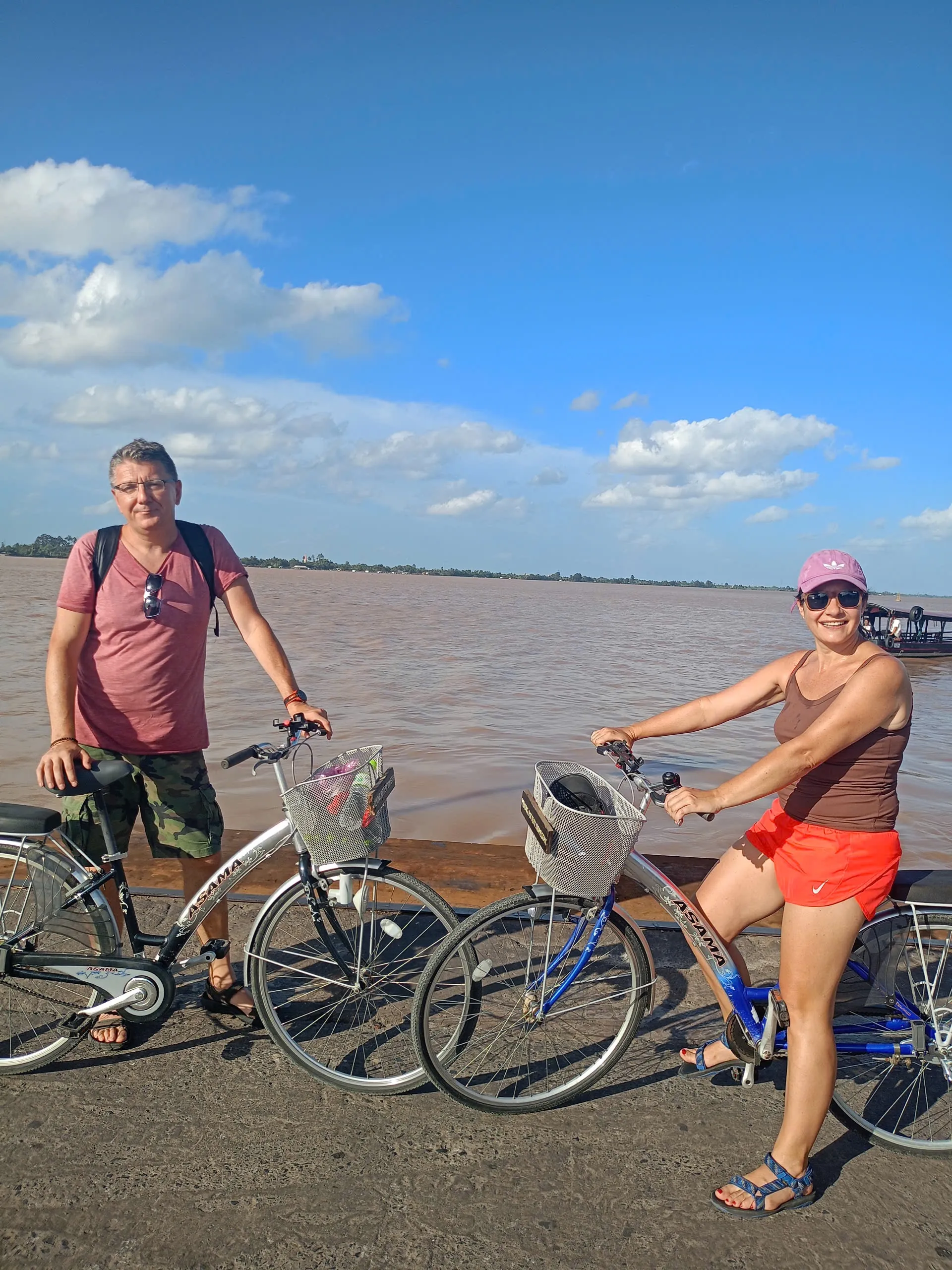 Couple with bicycles beside the wide Mekong River