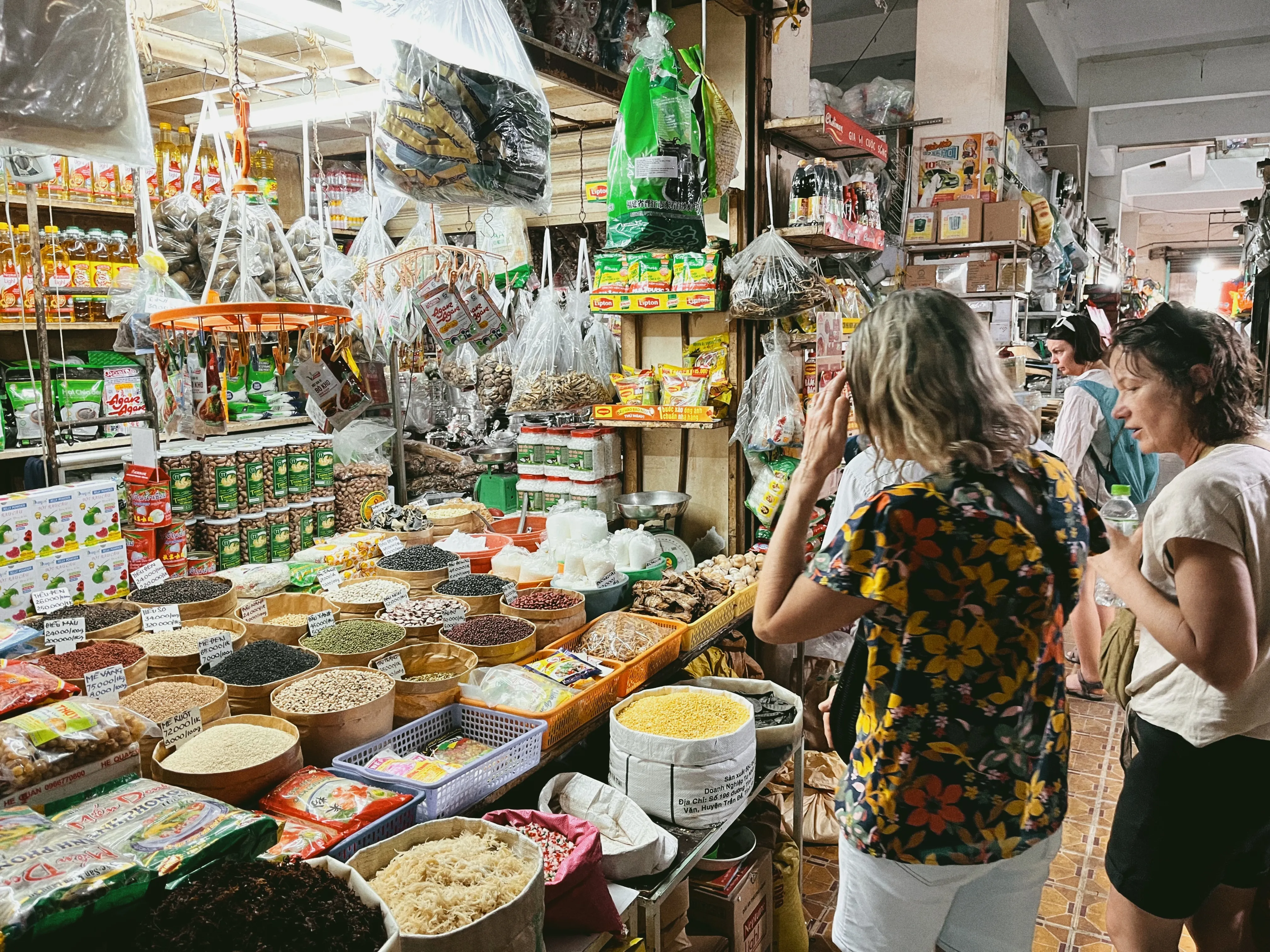 Travelers browsing spices and dried goods at a Mekong Delta market