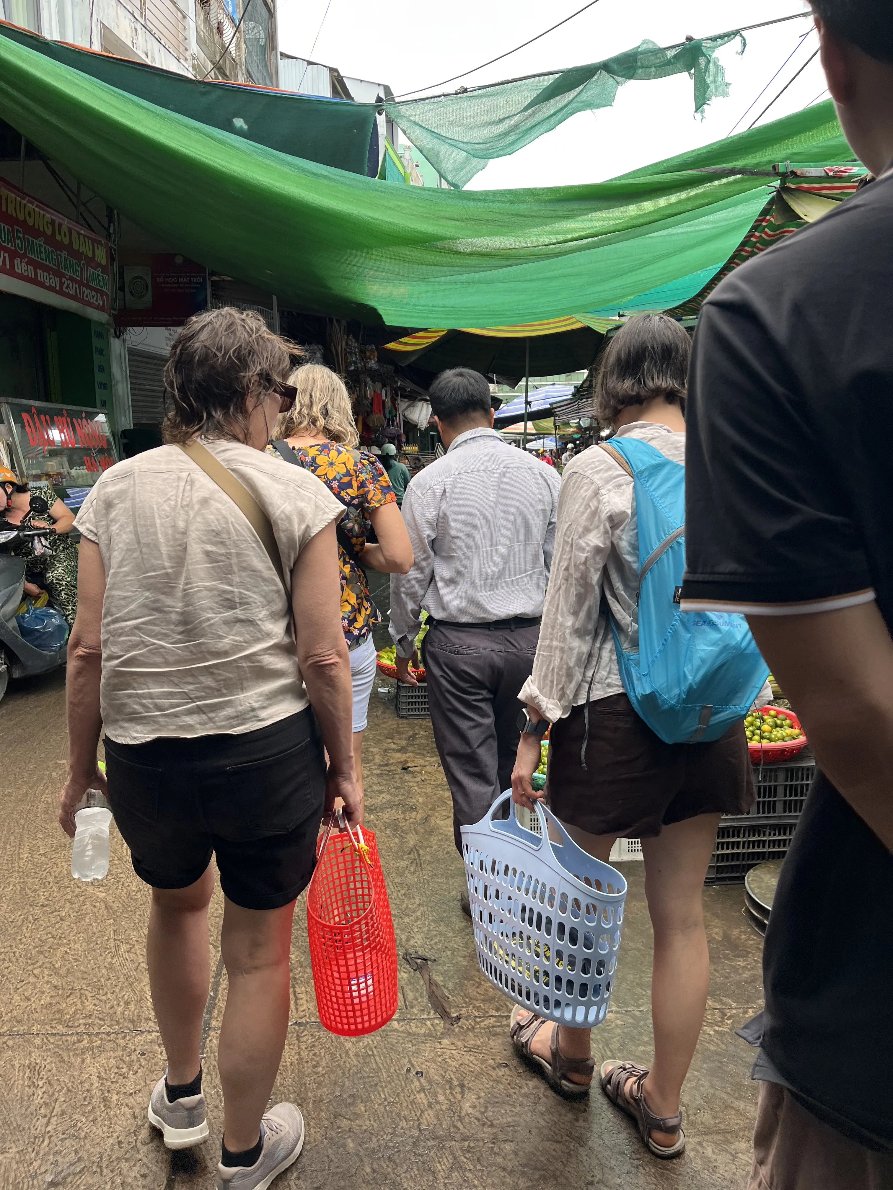 Visitors exploring a local market in Vinh Long with a friendly vendor
