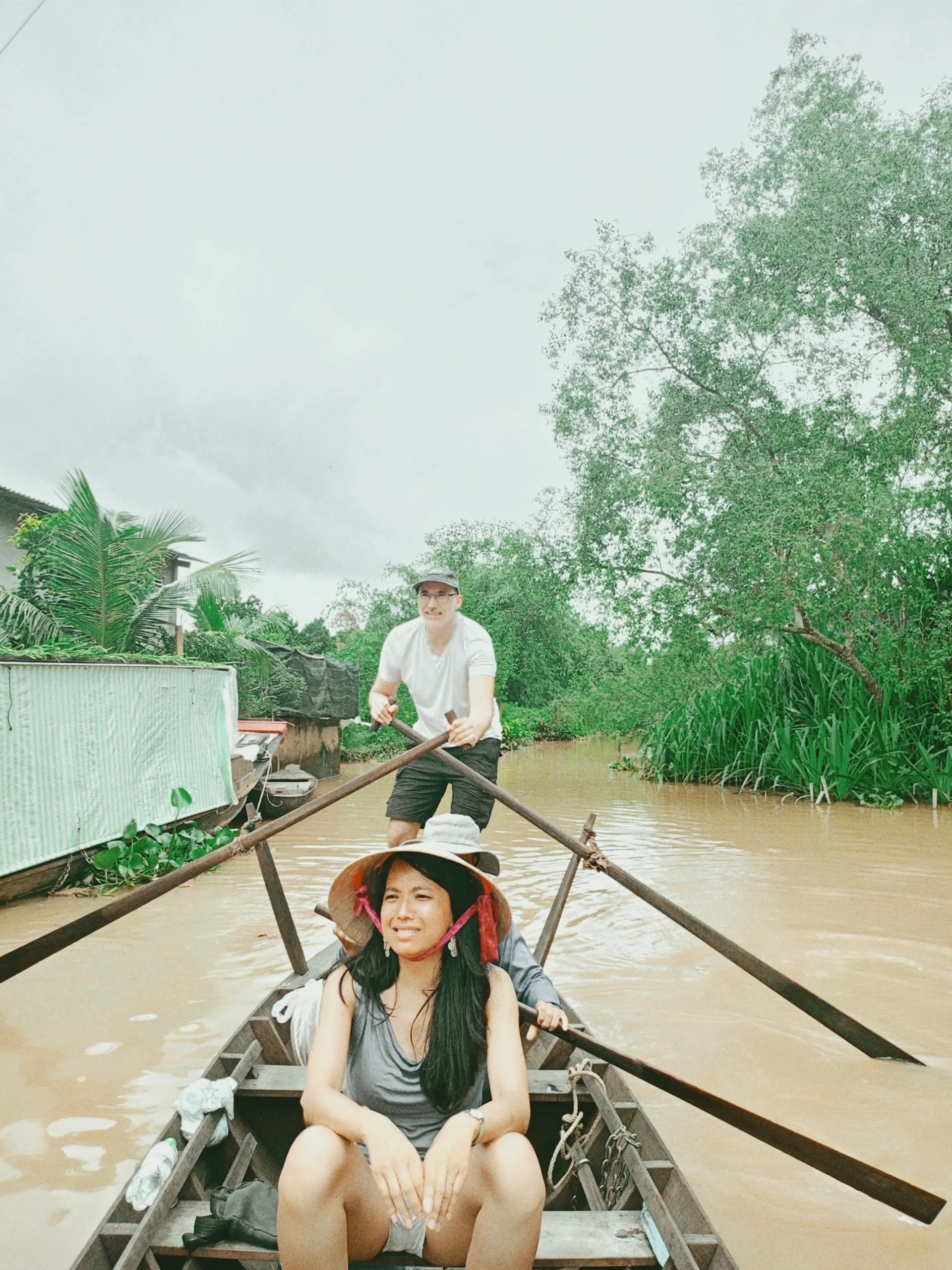 Couple enjoying a traditional rowing boat ride through a Mekong Delta canal