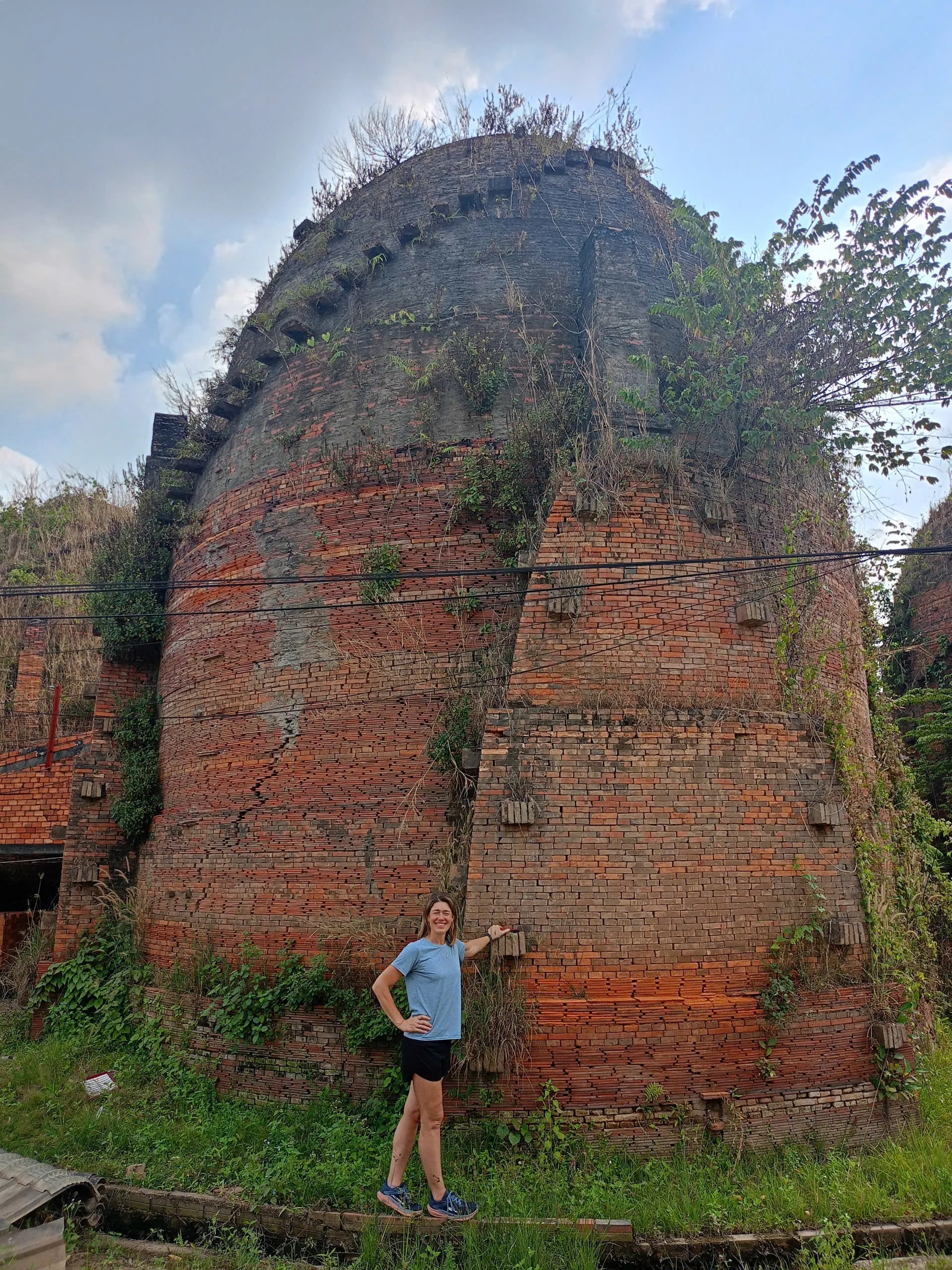 Traveler standing beside a towering red brick kiln in Mang Thit, Vinh Long