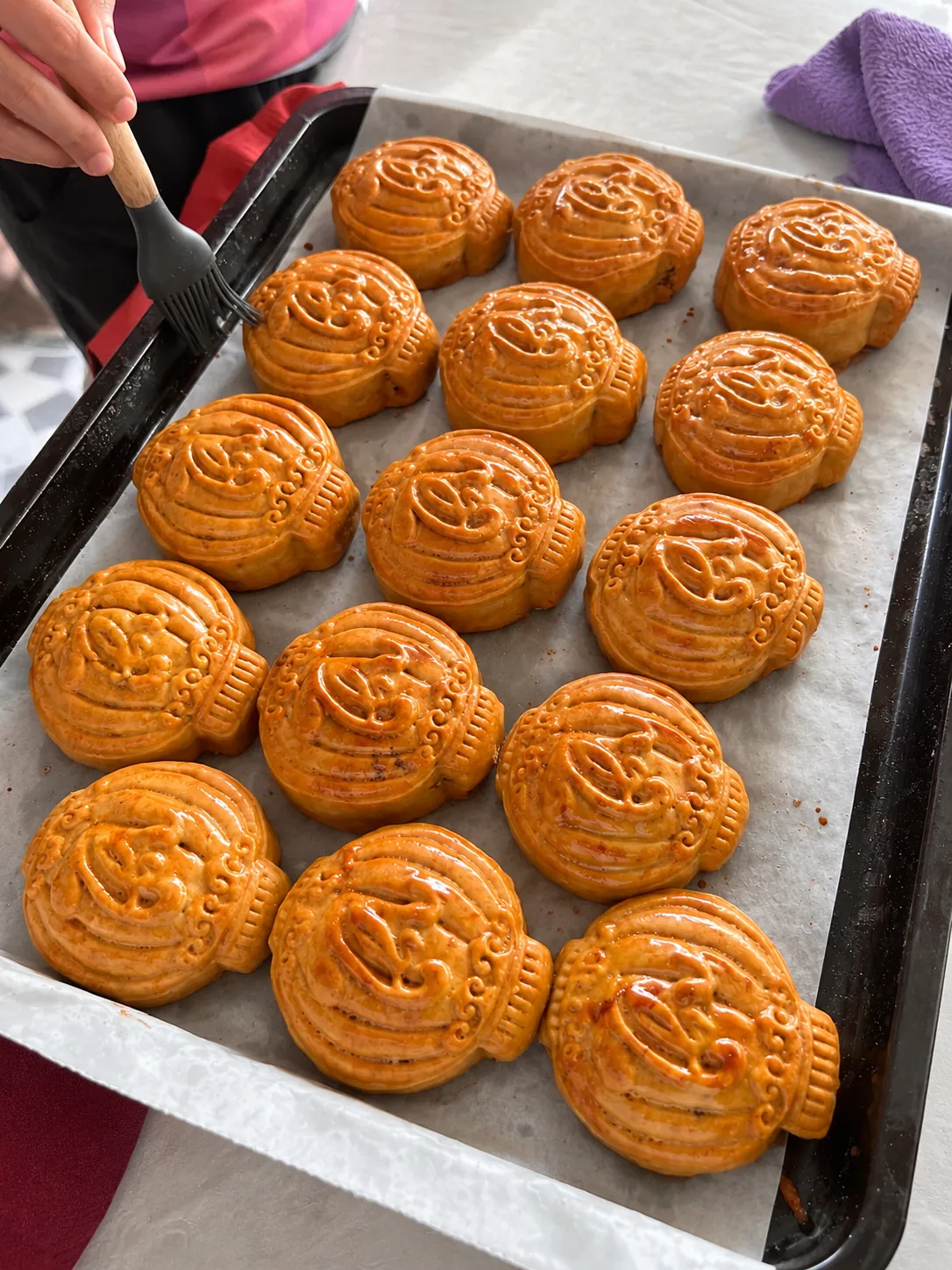 Traditional Vietnamese mooncakes being brushed before baking